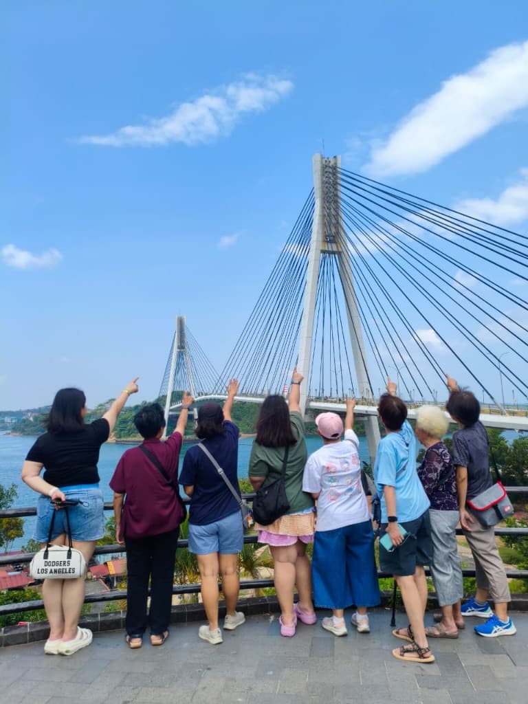 A tour group at the viewpoint railing, pointing across at the Barelang Bridge