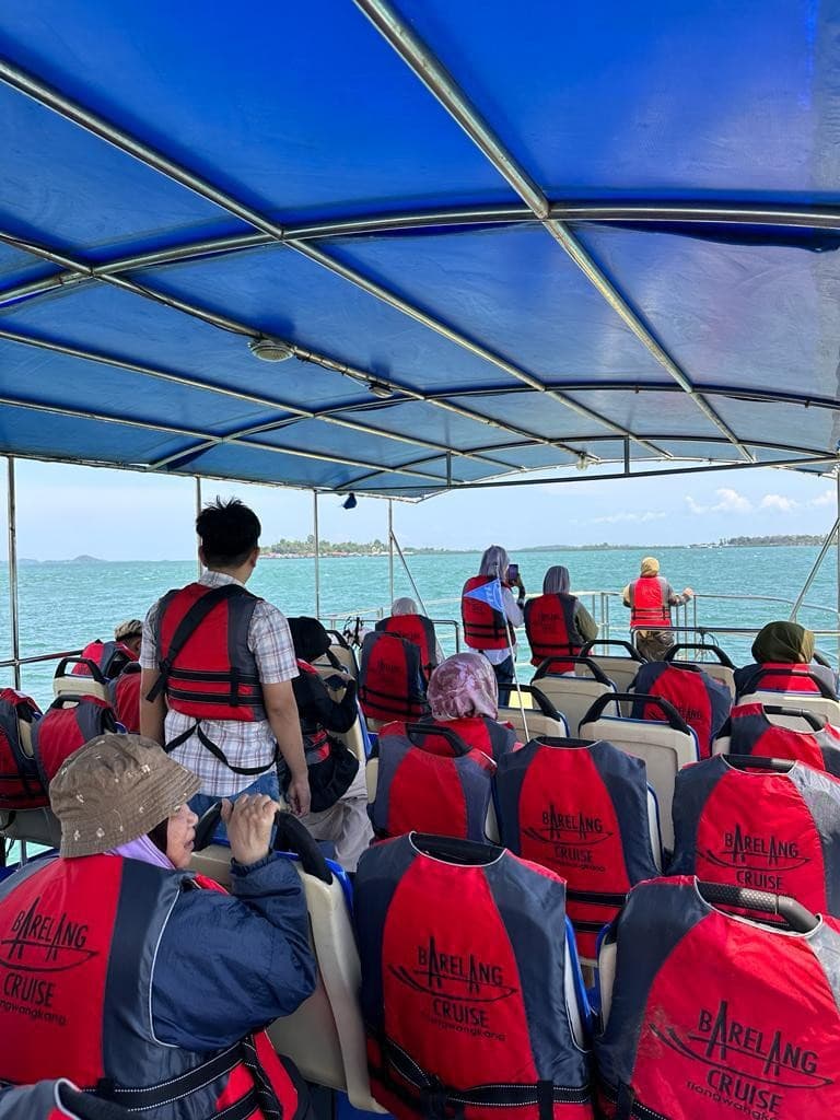 Guests in life jackets seated on a Barelang cruise boat under a blue canopy