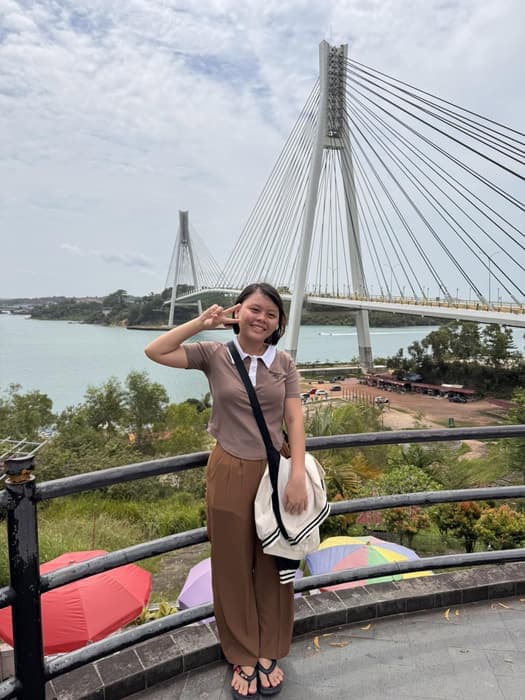 A traveller on the Barelang bridge viewing deck, with the bridge and the sea behind her.