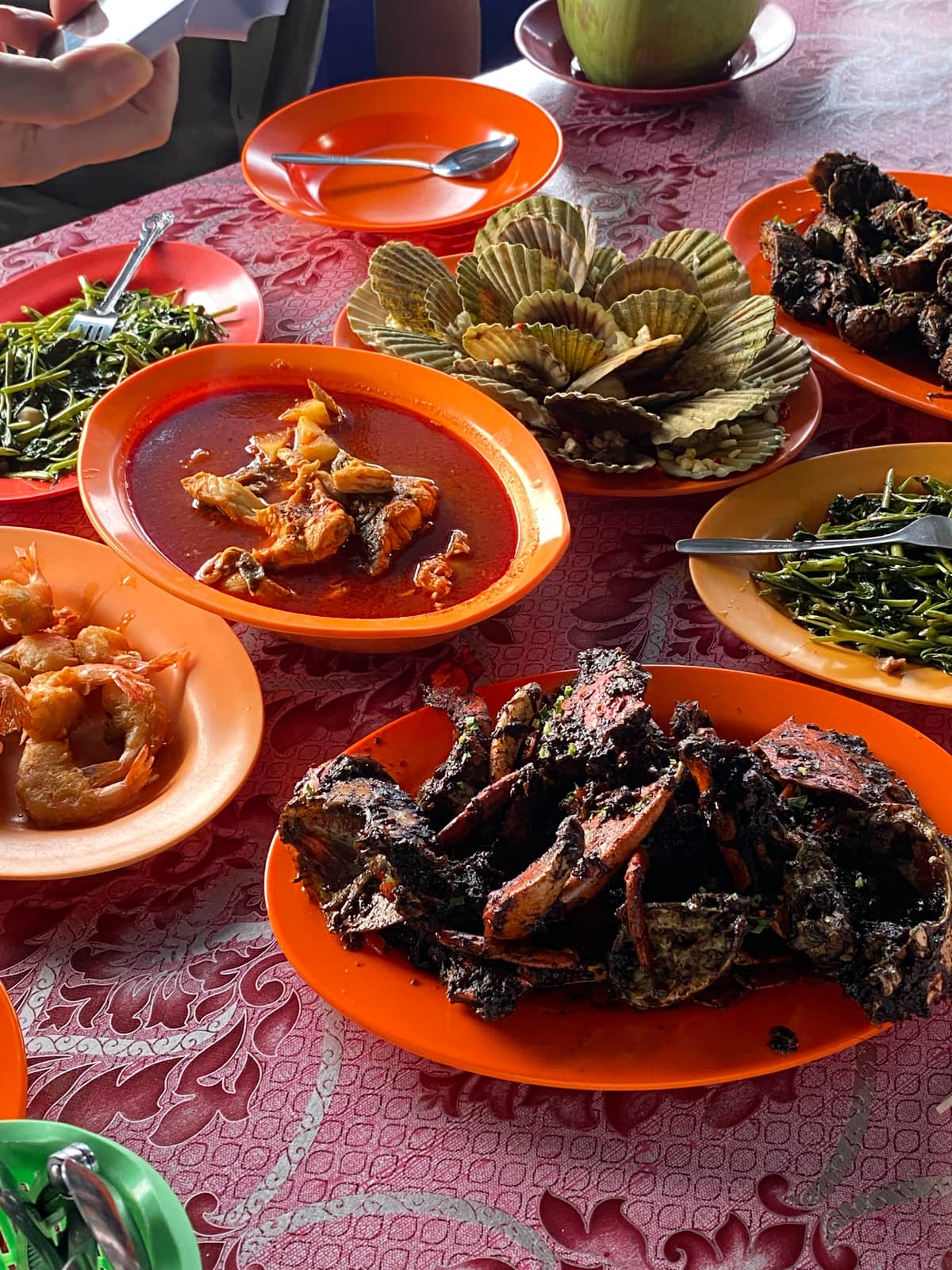 A table of chilli crab, scallops and greens at a seafood restaurant in Batam
