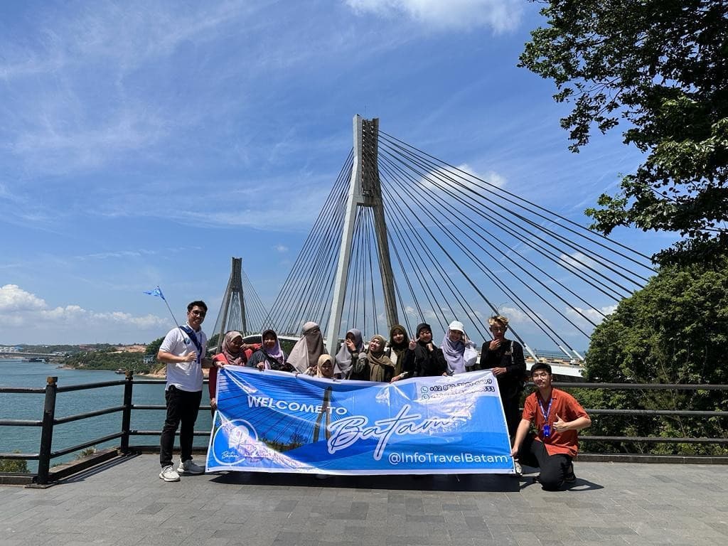 A tour group on a boat holding a Welcome to Batam banner